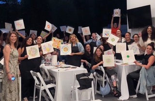 Photo of a group of business professionals holding up the artwork they completed during a workshop